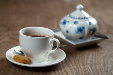 a cup of coffee with cookies and a sugar bowl on the table