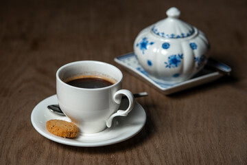 a cup of coffee with cookies and a sugar bowl on the table