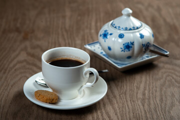 a cup of coffee with cookies and a sugar bowl on the table