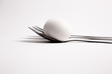 Chicken egg on metal forks, spoons isolated on white background close-up.
An egg that is set on top of two forks, spoons. Eggs have so many uses from diet to baking recipes.