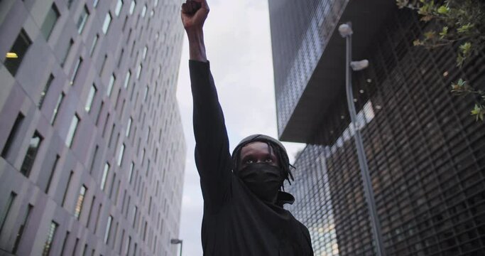 Young african american black man rasises his fists up in solidarity justice. 