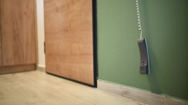 Apartment intercom phone hanging and swaying by the entrance door