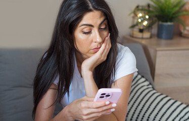 Beautiful Sad ,Worried  Unhappy  Woman Looking at her Smartphone at Home 