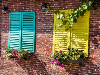 Beautiful brick house windows with colorful  shutters, flower pot and ivy, Provence, France 