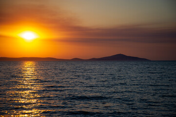 Fototapeta premium Sea and orange sky at sunset. Holiday landscape. Sun rays reflecting on the sea.
