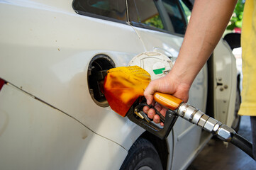 White car filled with fuel at the oil station.