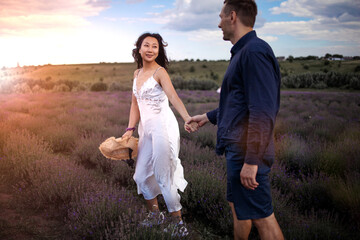 A young couple holding hands in the lavender field at sunset