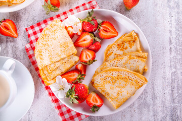 Traditional russian homemade thin pancakes blini crepes with fresh ripe strawberries