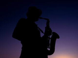 a musician playing the saxophone at sunset