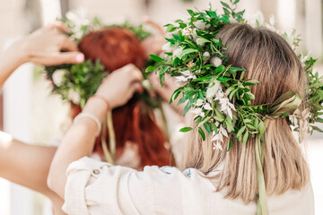 Obraz premium beautiful girl in wreath of flowers in meadow on sunny day. Portrait of Young beautiful woman wearing a wreath of wild flowers. Young pagan Slavic girl conduct ceremony on Midsummer. Earth Day