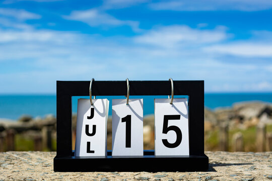 Jul 15 calendar date text on wooden frame with blurred background of ocean.