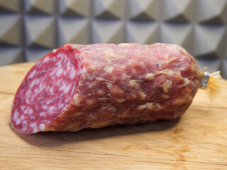 A large piece of smoked sausage on a wooden cutting board.