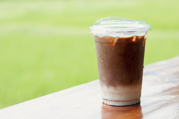 Iced coffee with milk, Mocha coffee in a plastic cup on a wooden table at a cafe. morning in a coffee shop with copy space for your text.