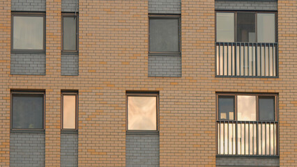 The facade of the new brick high rise apartment building with balconies. Stock footage. Brown brick house with windows.