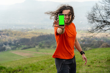 Young man standing and holding mobile phone on the hill