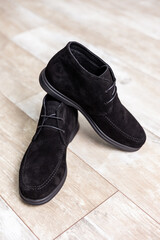 Black men's autumn boots, footwear material is genuine leather suede. Shoes isolated on the floor