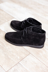 Black men's autumn boots, footwear material is genuine leather suede. Shoes isolated on the floor