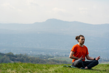 Fototapeta na wymiar Young man do yoga on the mountain peak