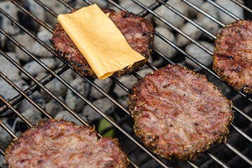 Selective focus of fresh delicious burger cutlets with cheese grilling on bbq grill