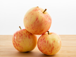 Fresh red apples on a wooden table with a white background.