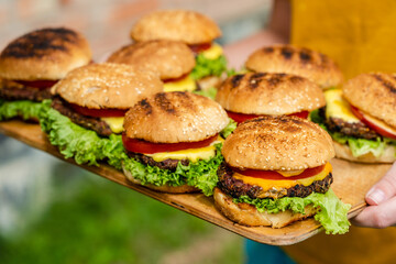 Closeup of homemade burgers made from fresh vegetables on wood plate holding women