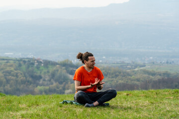 Fototapeta na wymiar Young smiling man sitting on the mountain peak