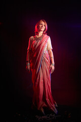 A beautiful European woman in a traditional Indian sari on a black background. Girl model posing in the studio