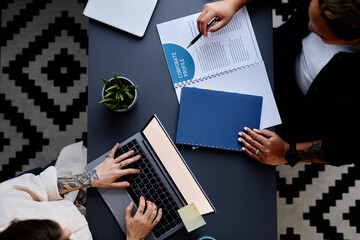 Graphic top view image of two businesswomen working at dark blue table with laptops and documents
