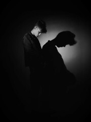 black and white portrait of a young man and the reflection of his silhouette on the wall