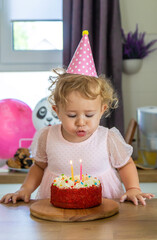 Child is two years old with a cake and candles. Selective focus.
