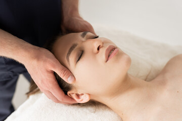 relaxed young woman on facial massage by specialist