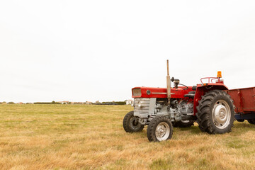 Tractor standing in a crop field. The day is cloudy. Concept of agriculture and rural life. Space for text.