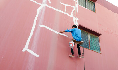 Work at height by Worker fixing cracks on wall, spreading plaster using trowel, Repair cracked...