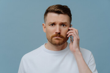 Worried man receiving bad news while talking with somebody on mobile phone