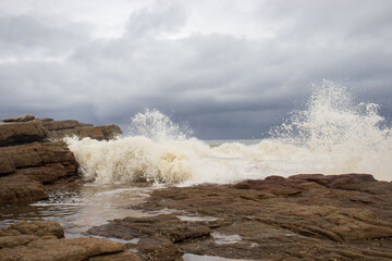 ocean water flowing onto rocks, causing the waves of water to crash onto the rocks
