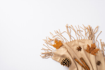 Obraz premium Autumn mood concept. Top view photo of cinnamon sticks yellow maple leaves anise and pine cone on beige scarf on isolated white background with copyspace