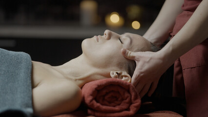 Spa treatments.Action.A young girl lying on towels who is being massaged with cream on different...