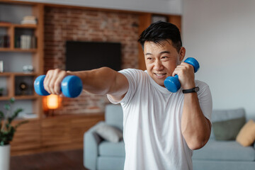 Fitness and sport concept. Active mature man exercising with two dumbbells and boxing, enjoying domestic workout