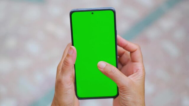 Closeup shot of Indian woman hand using mobile phone with Green screen, Finger swiping up in green screen of the mobile. Green screen mockup template of Mobile phone, Chroma key