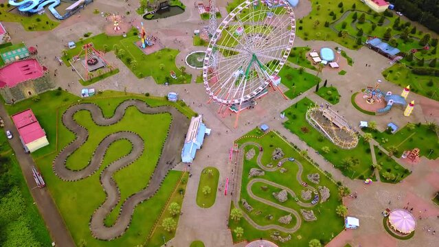 Top view of amusement park with Ferris wheel and roller coaster at sunset in Georgia at Tsitsinatela Park. Ferris wheel with air illumination. Recreation area of Georgian park on Black Sea coast.
