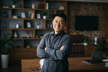 Happy confident handsome mature japanese businessman with crossed arms on chest in dark cabinet