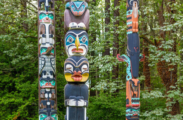 Native indigenous first nations totem poles in Stanley Park of Vancouver, British Columbia, Canada. - obrazy, fototapety, plakaty