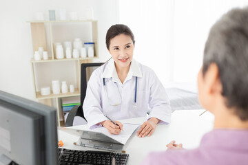 asian female doctor talk with old patient in mental health clinic, she screening and write patient information on patient chart, elderly healthcare promotion