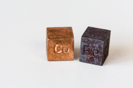 Iron and copper cubes with elements names on them on cream background