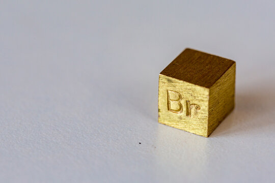 Brass cube with alloy name Br on it on cream background