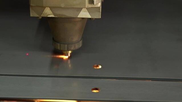 Close-up CNC laser cutting machine. 
The metal sheet is cut on the cnc machine and holes are drilled on it. Laser cutting device following laser light and laser light.  Cutting of industrial metal par