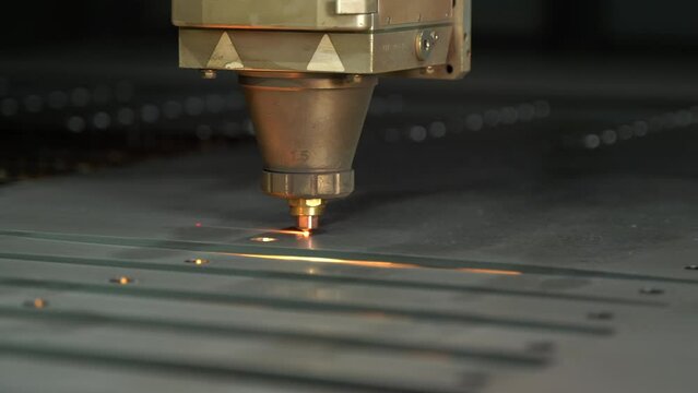 Close-up CNC laser cutting machine. 
The metal sheet is cut on the cnc machine and holes are drilled on it. Laser cutting device following laser light and laser light.  Cutting of industrial metal par