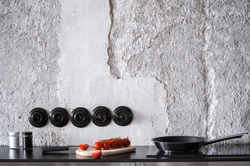 frying pan on induction hob and tomato on countertop in kitchen