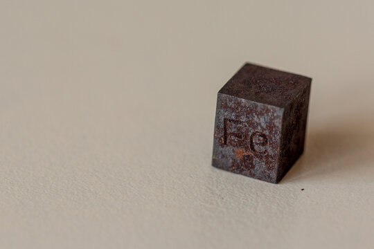 Iron cube with element name Fe on it on cream background