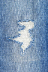 Torn jeans denim background texture. Blue jeans fabric as material surface